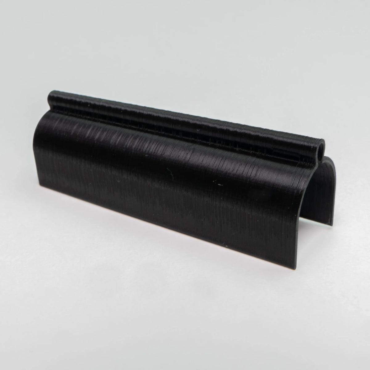 Angled view of the black Test Tube Cover showing its curved snap-fit design and anti-roll side